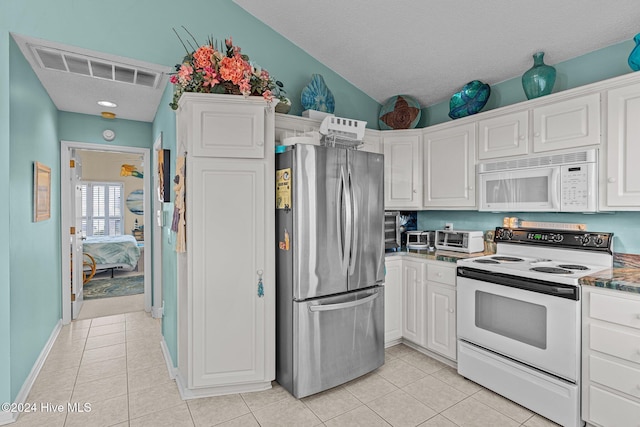 kitchen featuring white appliances, white cabinets, vaulted ceiling, light tile patterned flooring, and light stone counters