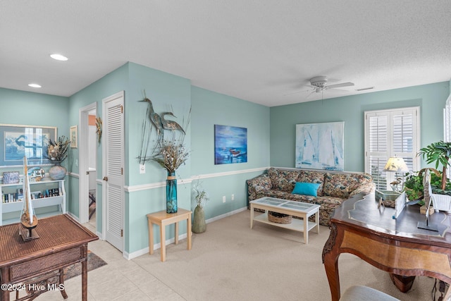 carpeted living room with ceiling fan and a textured ceiling