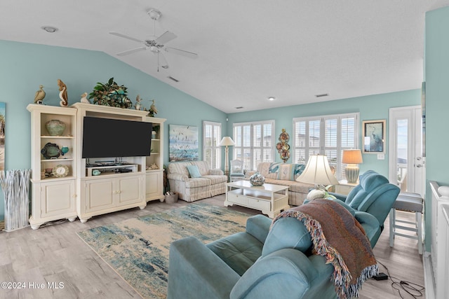 living room featuring ceiling fan, lofted ceiling, a textured ceiling, and light hardwood / wood-style flooring