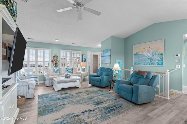 living room with a textured ceiling, light wood-type flooring, ceiling fan, and lofted ceiling