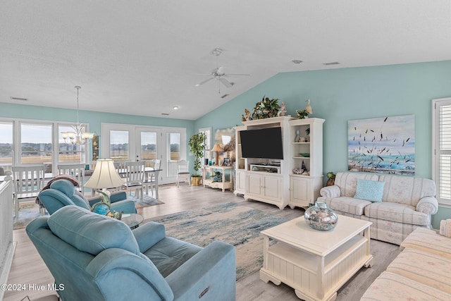 living room featuring french doors, ceiling fan with notable chandelier, vaulted ceiling, and hardwood / wood-style flooring