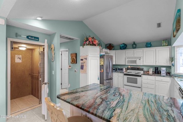 kitchen featuring white cabinets, a kitchen bar, white appliances, and vaulted ceiling