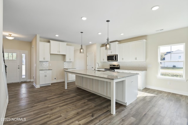 kitchen with a healthy amount of sunlight, a center island with sink, white cabinets, and stainless steel appliances