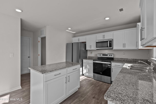 kitchen featuring white cabinets, appliances with stainless steel finishes, a center island, and stone counters