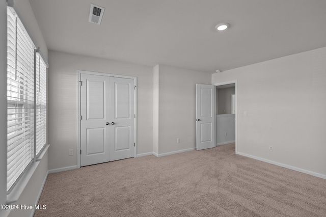 unfurnished bedroom featuring light colored carpet and a closet