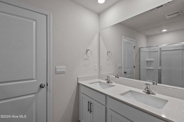 bathroom featuring a shower with shower door and vanity