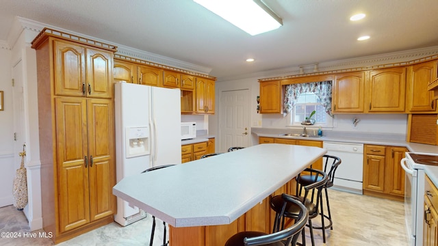 kitchen with a kitchen breakfast bar, white appliances, crown molding, sink, and a center island