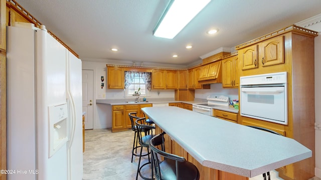 kitchen with a breakfast bar area, a kitchen island, white appliances, and ornamental molding