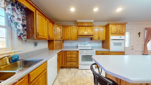 kitchen featuring a kitchen breakfast bar, sink, white appliances, and ornamental molding