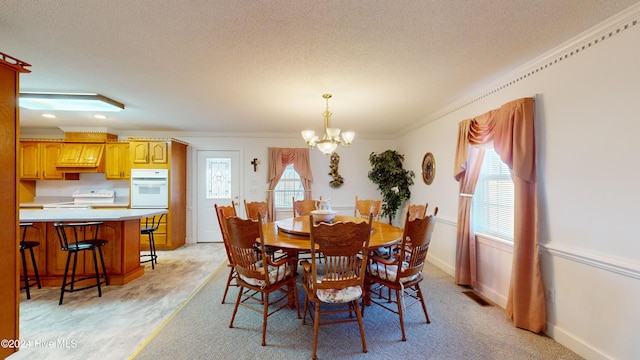 carpeted dining room with a wealth of natural light, crown molding, a textured ceiling, and a notable chandelier