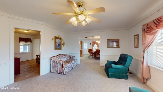 living room with light carpet, plenty of natural light, ceiling fan, and ornamental molding