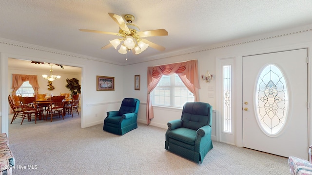 entryway featuring carpet, a textured ceiling, ceiling fan with notable chandelier, and crown molding