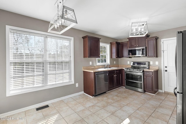 kitchen featuring pendant lighting, stainless steel appliances, light tile patterned floors, and sink