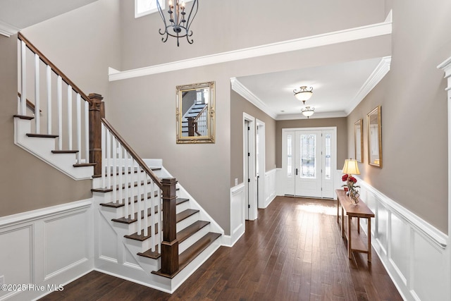 entrance foyer with dark hardwood / wood-style flooring, crown molding, and an inviting chandelier