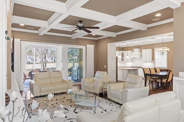 living room with ceiling fan with notable chandelier, crown molding, light wood-type flooring, beam ceiling, and coffered ceiling