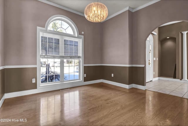 unfurnished room with hardwood / wood-style floors, ornamental molding, and a notable chandelier