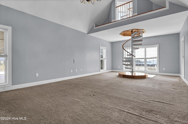 unfurnished living room featuring carpet flooring, high vaulted ceiling, and an inviting chandelier