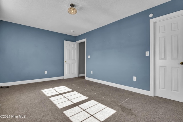 unfurnished bedroom with dark colored carpet and a textured ceiling