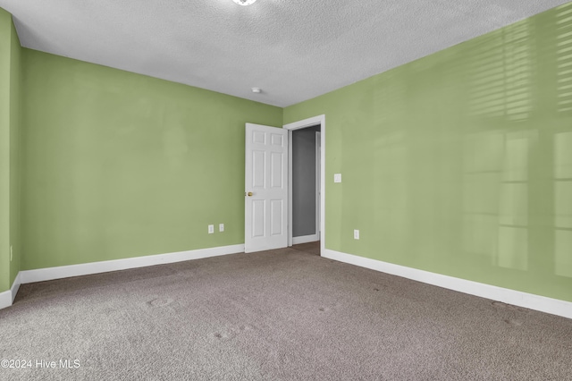 carpeted empty room featuring a textured ceiling