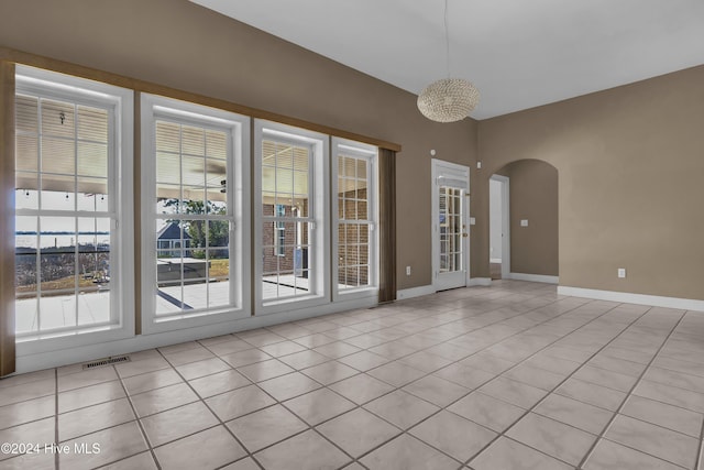 empty room with light tile patterned flooring and an inviting chandelier