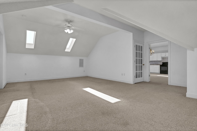 bonus room featuring light carpet, lofted ceiling with skylight, and ceiling fan with notable chandelier