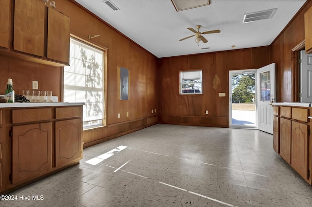 kitchen with ceiling fan, wood walls, and a textured ceiling