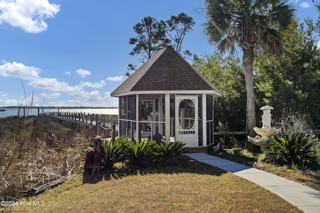 view of outdoor structure featuring a water view and a lawn