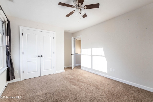 unfurnished bedroom with ceiling fan, light colored carpet, and a closet