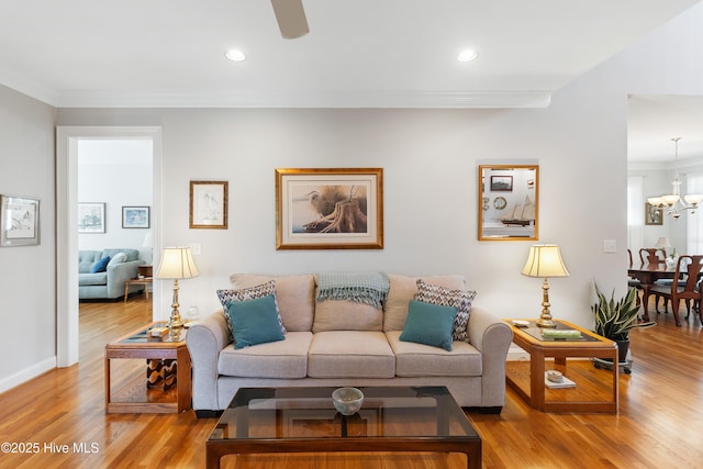 living room with light hardwood / wood-style floors, ornamental molding, and a notable chandelier