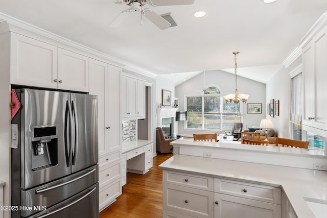 kitchen with tasteful backsplash, stainless steel refrigerator with ice dispenser, vaulted ceiling, white cabinets, and ceiling fan with notable chandelier