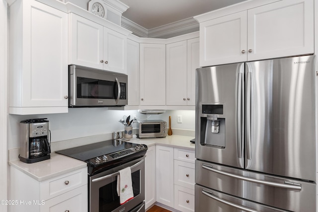 kitchen with white cabinets, appliances with stainless steel finishes, and ornamental molding