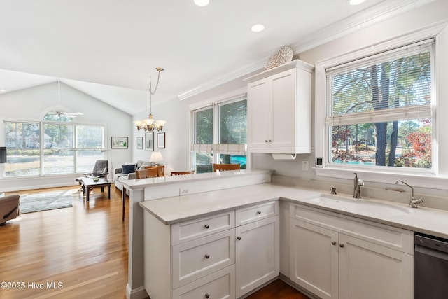 kitchen featuring kitchen peninsula, stainless steel dishwasher, vaulted ceiling, sink, and white cabinetry