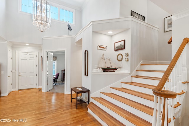 foyer with a towering ceiling, light hardwood / wood-style flooring, and a notable chandelier