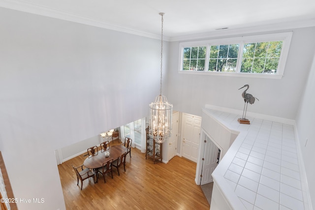 dining space with light hardwood / wood-style floors, crown molding, and a chandelier