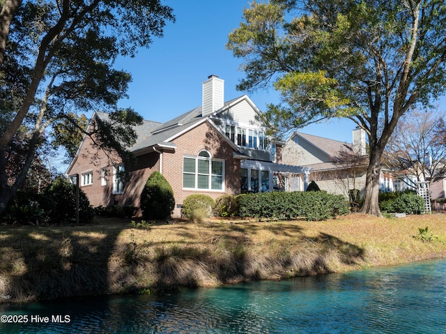 rear view of house with a yard and a water view