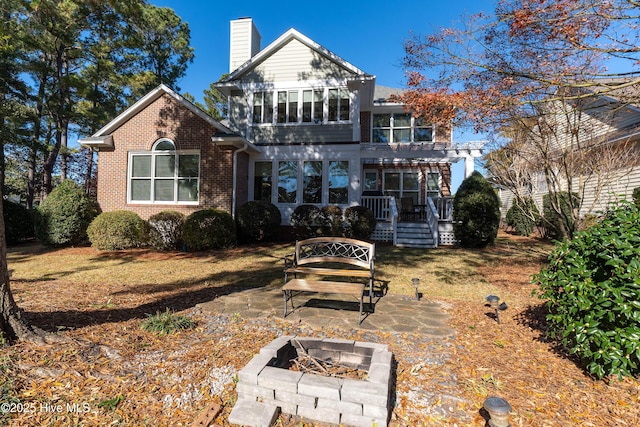 view of front of house with a fire pit and a pergola