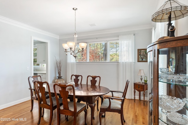 dining area with a notable chandelier, light hardwood / wood-style floors, and crown molding