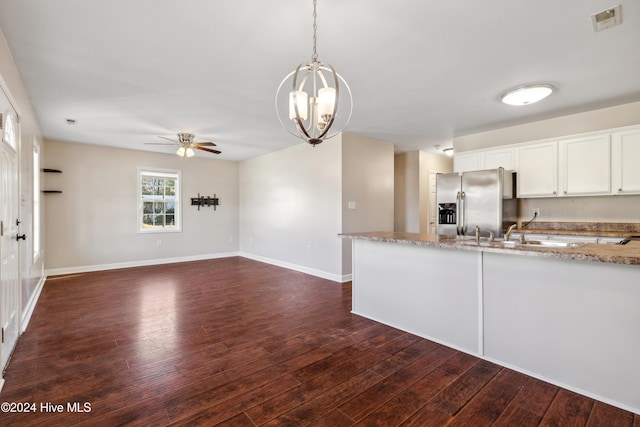 kitchen with light stone countertops, sink, dark wood-type flooring, stainless steel fridge, and white cabinets