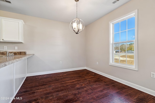 unfurnished dining area with a chandelier and dark wood-type flooring