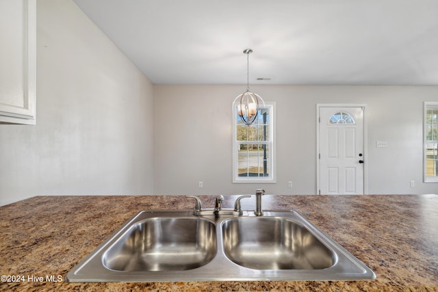 kitchen with white cabinetry, an inviting chandelier, hanging light fixtures, and sink