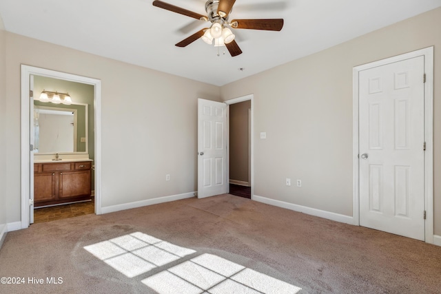 unfurnished bedroom with ceiling fan, a closet, light carpet, and ensuite bath