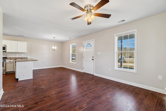 interior space with dark wood-type flooring and ceiling fan with notable chandelier