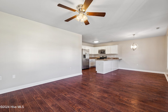 unfurnished living room with ceiling fan with notable chandelier and dark wood-type flooring