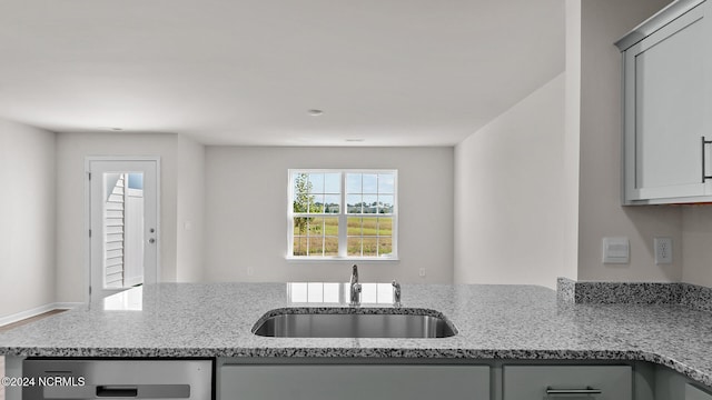 kitchen featuring gray cabinetry, light stone countertops, sink, and dishwasher