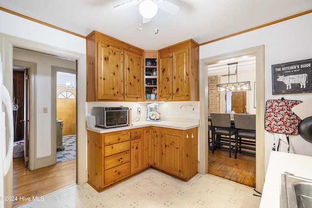 kitchen featuring pendant lighting, ceiling fan with notable chandelier, light hardwood / wood-style floors, and crown molding