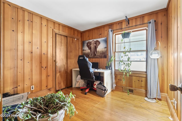 office area featuring light wood-type flooring, ornamental molding, and wooden walls