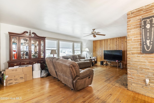 living room featuring ceiling fan, hardwood / wood-style floors, and wooden walls