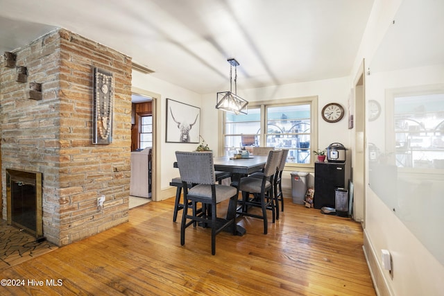 dining space featuring light wood-type flooring and a brick fireplace