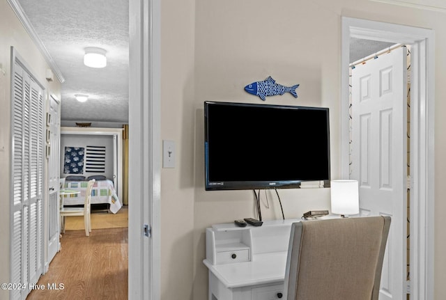 office area featuring a textured ceiling, light hardwood / wood-style floors, and crown molding