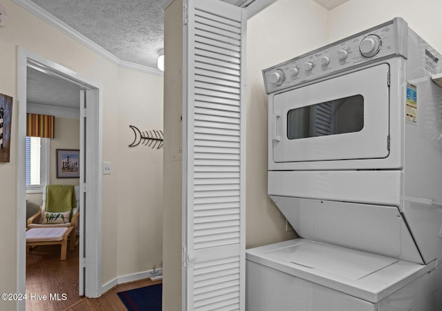 clothes washing area featuring a textured ceiling, wood-type flooring, ornamental molding, and stacked washer / dryer